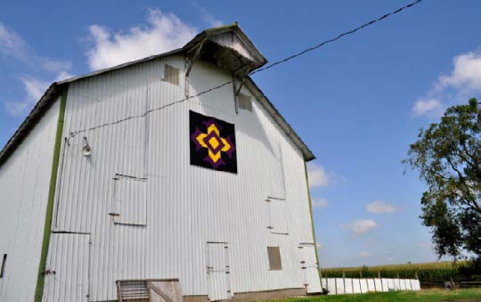 “God’s Eye” in Madison Township. The building which features this barn quilt was built 130 years ago and features square pegs and native stone. The original owners raised purebred stallions, and sales attracted buyers from many states. Local firefighters practiced getting enough pressure to shoot a stream over the top of the building. The block celebrates the importance of the Madison Church of Christ in the life of the community. Photo courtesy of Janet Carl. 