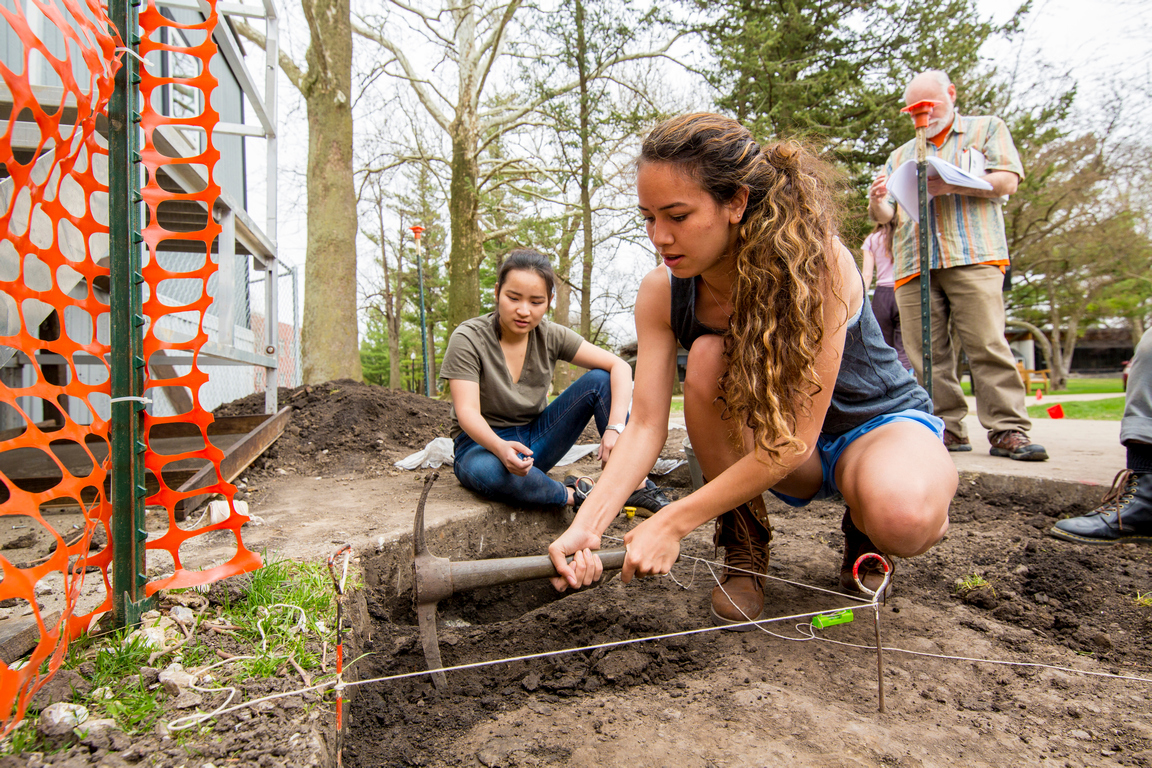 Second-year Grinnell student Lauren Edwards digs for the Peace Rock in the area where Byron Hueftle-Worley’s research said it would be, near new construction on the College’s Quad. Photo by Justin Hayworth.