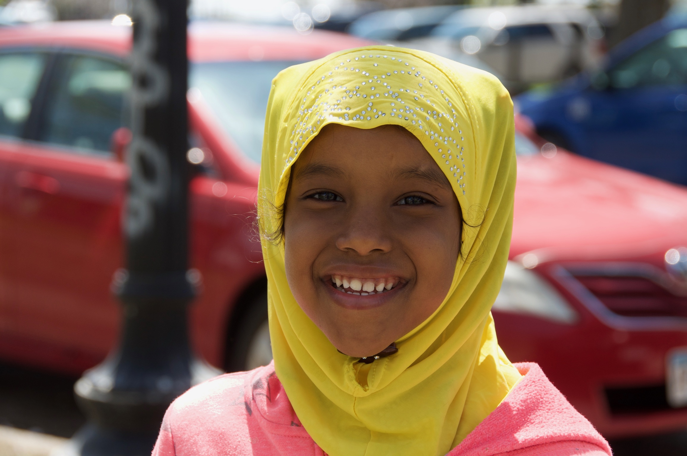 A beautiful young girl in a bright hijab accompanies her mother on errands