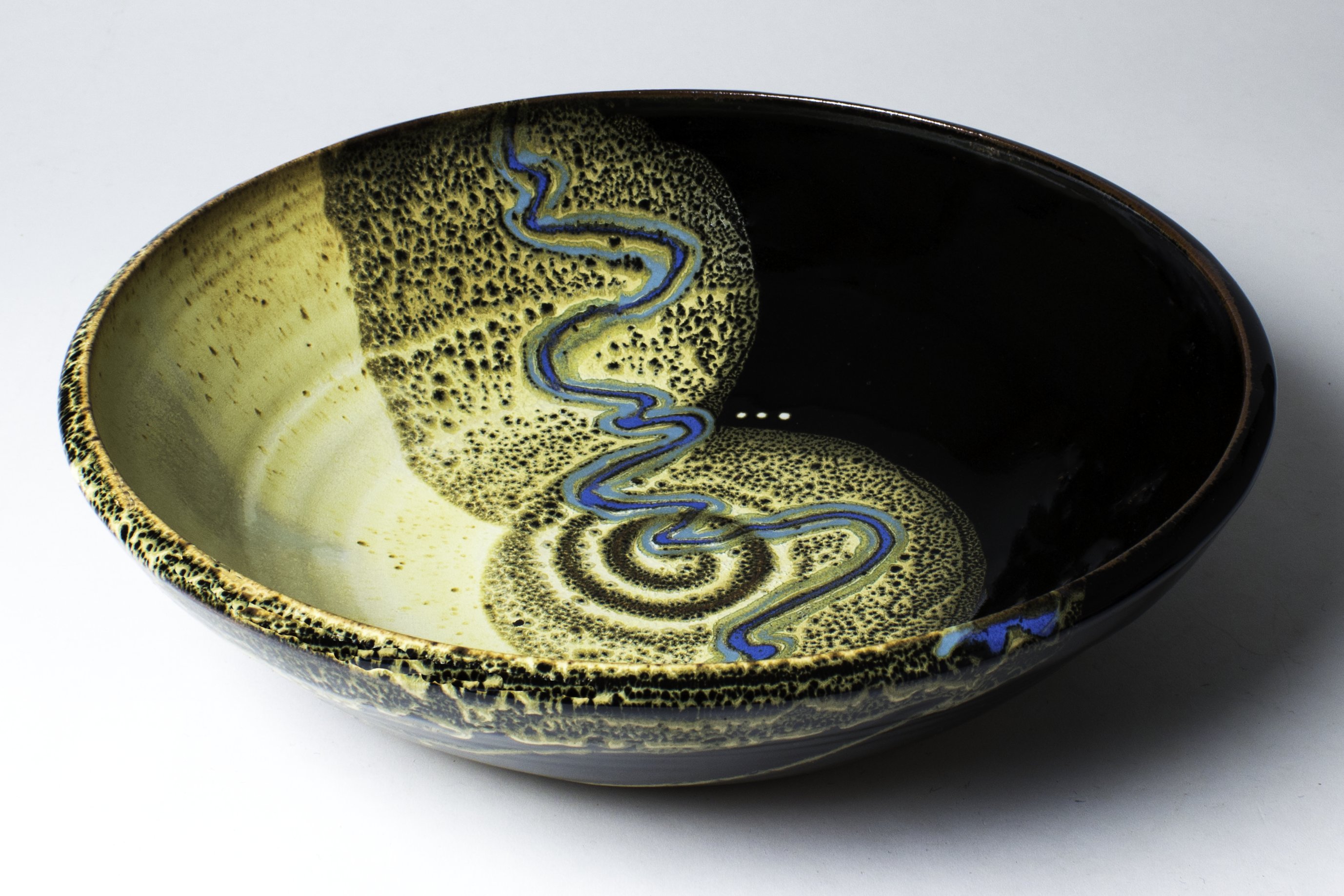 Smith grinds her own glazes from locally available minerals. Her primary ingredients include silica, feldspar, talc, red iron oxide and cobalt. This piece is glazed in her 'Yellow-stone' pattern