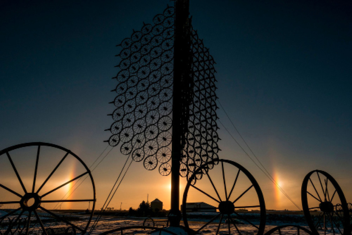 Sundogs flanking L. J. Maasdam's wheel sculpture outside Sully, Iowa. Photo by Justin Hayworth