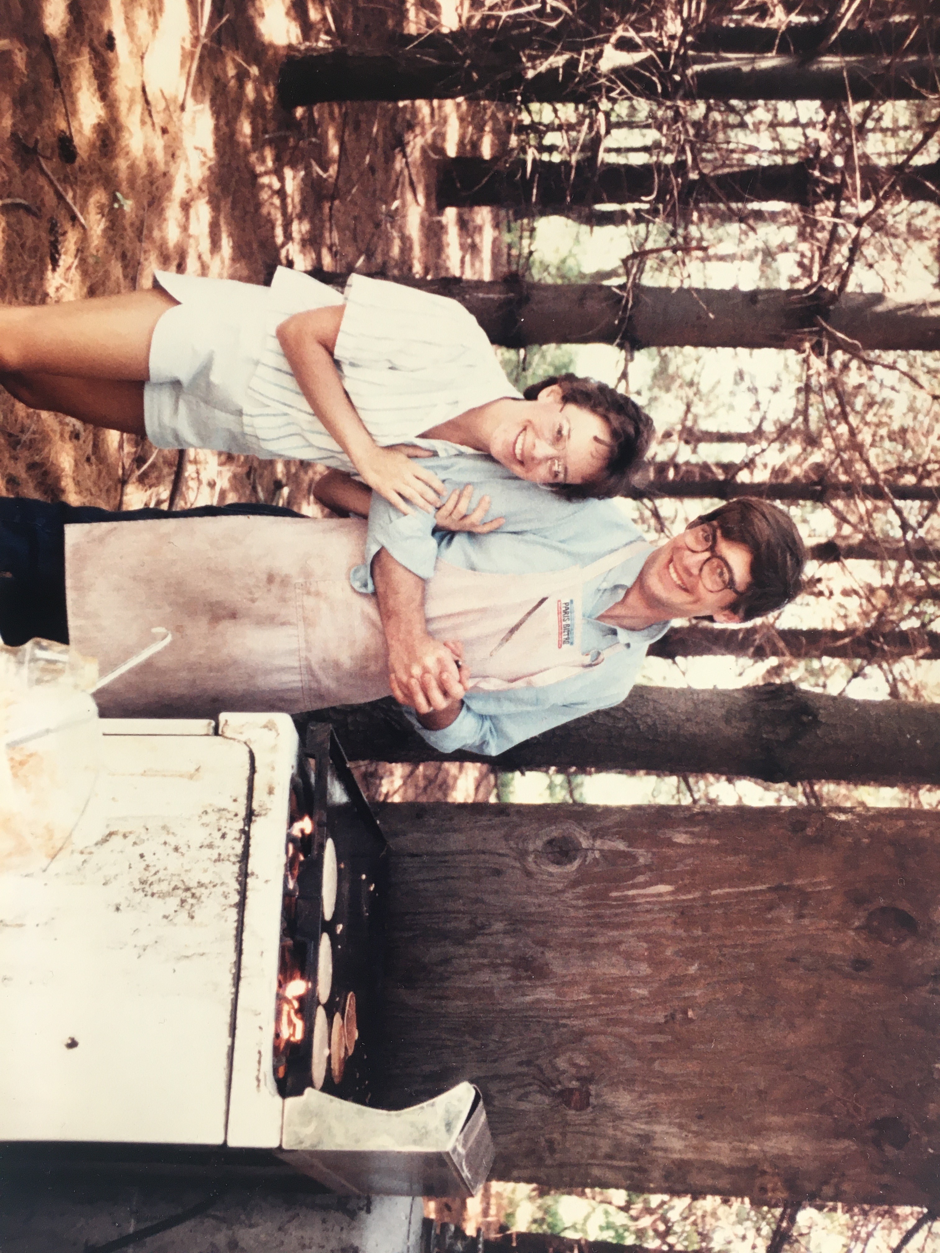 A person and person standing in front of a barbecue