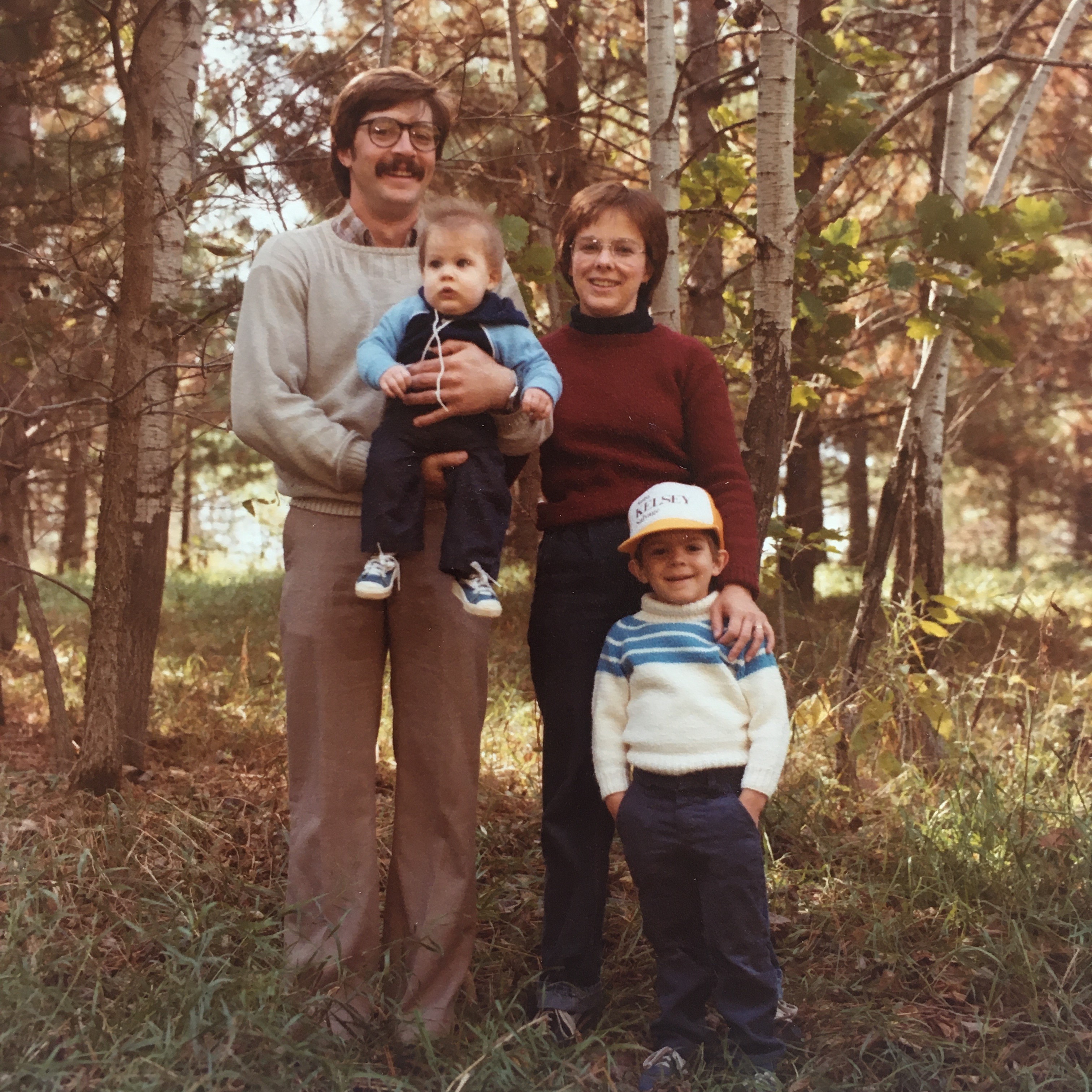 A person and person standing in a forest with two children